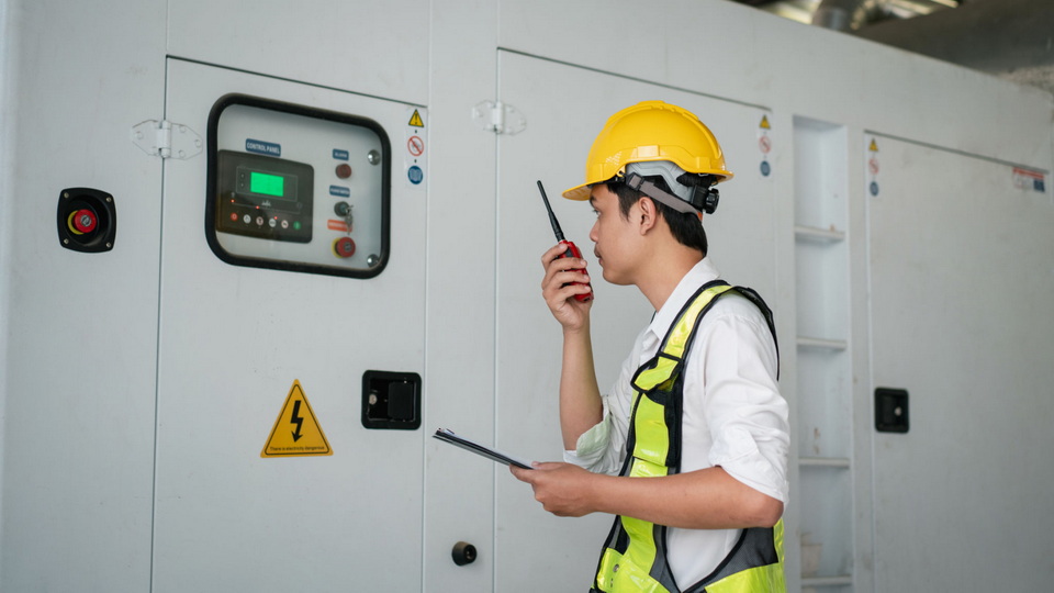 A technician inspecting a diesel generator's control panel