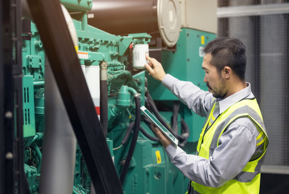 A technician inspecting a generator's engine